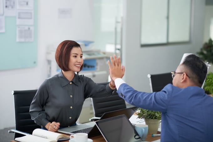 asian-man-woman-business-attire-sitting-table-meeting-room-doing-high-five