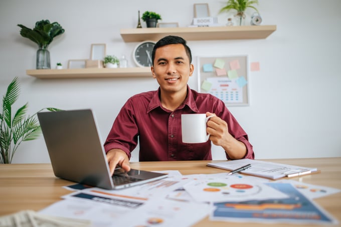 man-working-with-laptop-holding-coffee-cup